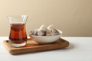 Traditional Turkish tea in glass and sweets on white wooden table, closeup. Space for text