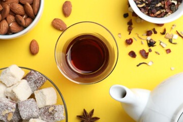 Flat lay composition with traditional Turkish tea, and sweets on yellow background