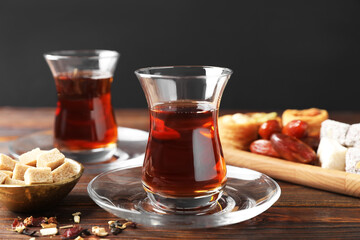 Traditional Turkish tea, brew, sugar and sweets on wooden table, closeup