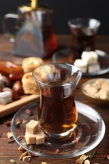 Traditional Turkish tea, brown sugar and sweets on wooden table, closeup