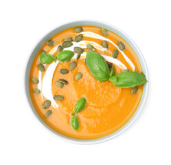 Delicious pumpkin soup with seeds and basil in bowl isolated on white, top view