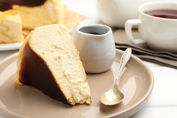 Piece of delicious Basque cheesecake, chocolate sauce and tea on white wooden table, closeup