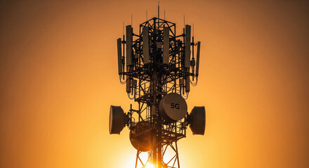 Silhouette of 5G Cell Tower and Antenna Array Against a Bright Orange Sunset