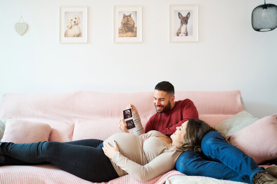 Expecting couple viewing baby ultrasound on couch