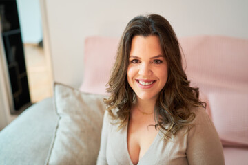 Young woman smiling, looking at camera comfortably at home