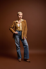 Fototapeta premium Young beautiful woman shows off fashionable style in a stylish brown studio