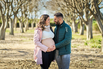 Pregnant couple embracing outdoors, expecting baby