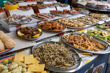 Delicious fresh cooked street food on daily food market in Palermo, Sicily, travel destination, food tourism Italy, variety of raw, roasted, grilled fish, seafood, calamari, sea urchins