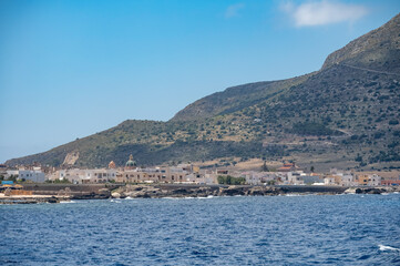 Boat trip and view on coastline of Favignana island with small village, shallow bays with clear turquoise water, tuff rocks, abandoned quarries, caves, Egadi Islands near Sicily, Italy