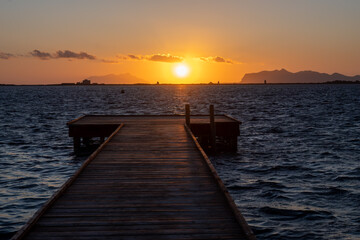 Fototapeta premium Sunset at Stagnone of Marsala, brackish lagoon and nature reserve near Marsala, Sicily, Italy, unique ecosystem with shallow, warm water, salt pans, and ancient windmills.