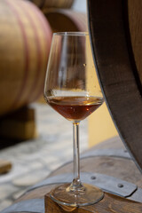 Visit of wine cellar with old large oak barrels, glass of fortified dry or sweet tasty marsala wine from barrels in Marsala, Sicily, Italy