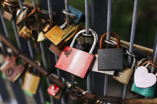 Colorful love locks attached to metal fence. Symbol of romance, loyalty, and commitment. Tradition of couples locking padlocks as sign of eternal love.