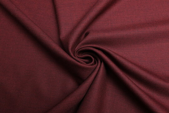 Close-up of luxury burgundy cool wool suiting fabric, intricately woven with black thread to create a rich melange effect and dynamic color depth, highlighting the material's premium texture and drape - Powered by Adobe
