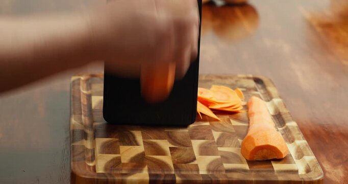 Close-up of hands slicing fresh carrot on a wooden cutting board with a grater, preparing healthy vegan meal ingredients, home cooking process, natural food, rustic kitchen atmosphere, healthy