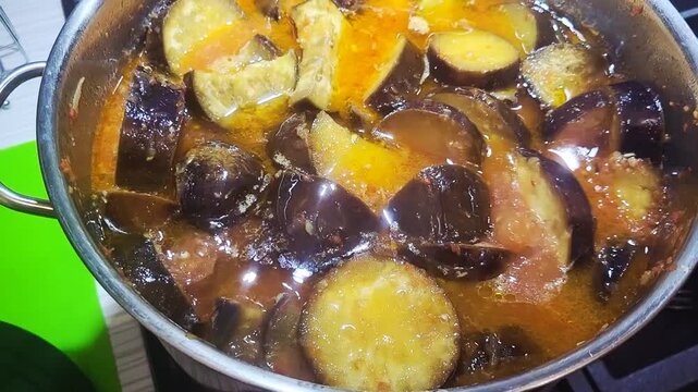 Cooking a comforting eggplant stew with fresh spices in a cozy kitchen setting