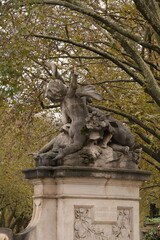Fototapeta premium Historic Stone Statue Surrounded By Trees In A Düsseldorf Park Monument Scene At Dusk
