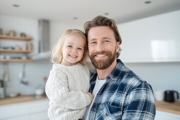Fototapeta premium Smiling father holding young daughter in modern kitchen at home, happy family moment in natural light