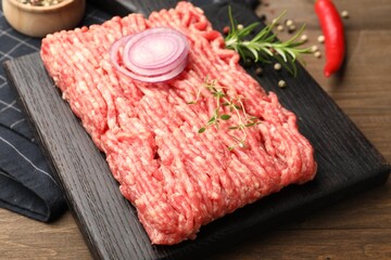 Raw minced meat with rosemary, thyme and spices on wooden table, closeup