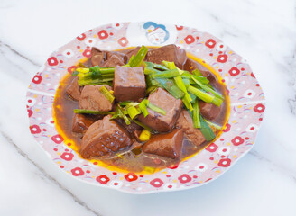 Indulge in this rich, savory braised duck blood dish, perfectly cubed and coated in a glossy sauce, topped with vibrant green onions. A culinary delight for any table.