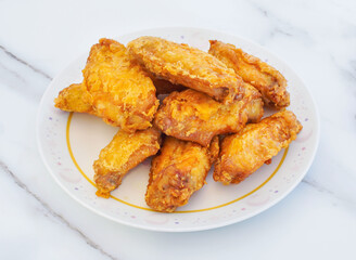 Savor the irresistible crunch of golden fried chicken wings, perfectly piled on a decorative plate, promising a delightful culinary experience for any occasion.