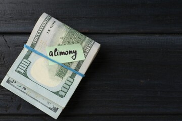Note with word Alimony and money on wooden table, top view. Space for text