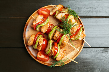 Skewers with grilled chicken and vegetables on wooden table, top view