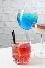 Glasses of tasty cocktails on white table, closeup