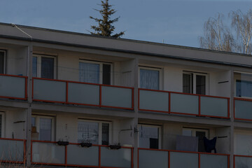 shared balconies lined with hanging laundry and rusted red railings, multistory housing block showing everyday routines and community life, authentic neighborhood texture for social and urban