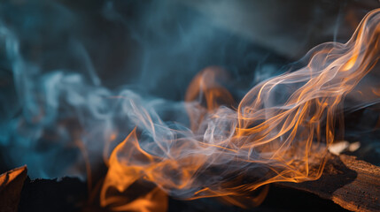 A close up shot showing wisps of smoke and bright orange flames against a dark background