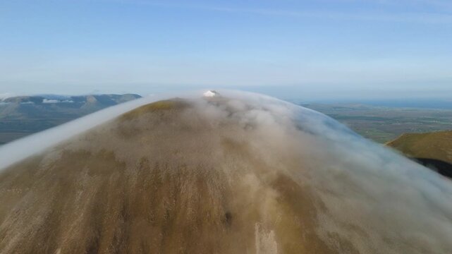 Amazing 4K aerial video of flying above and around Most Famous mountain in Ireland - Croagh Patrick in windy weather, with moving fog and clouds with breathtaking views around, Westport, Ireland