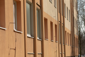 orange building facade, tall windows in sunny apartment, residential block with soft sunlight and repeating windows, warm orange exterior featuring rhythmic windows and textured plaster walls