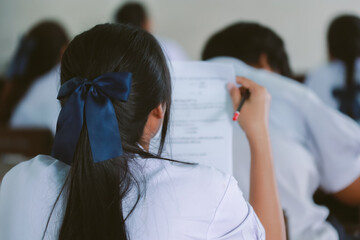 Students writing and reading exam answer sheets exercises in classroom of school with stress