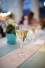 Close-up of glass of champagne on wooden table in cafe interior, soft light.