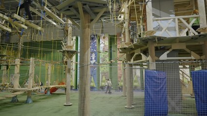 Visitors walking on rope bridges in adventure park. Creative