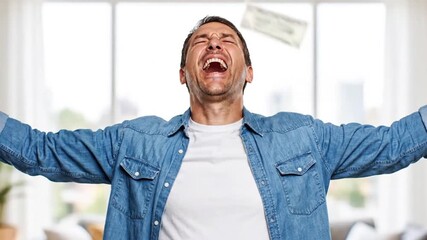 An ecstatic and overjoyed man in a denim shirt celebrates a financial windfall, shouting with pure joy and arms outstretched as money rains down. A concept of success, winning the lottery.
