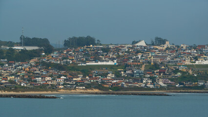 Obraz premium Coastal townscape with colorful houses nestled on a hillside overlooking the sea. A serene, sunny day scene
