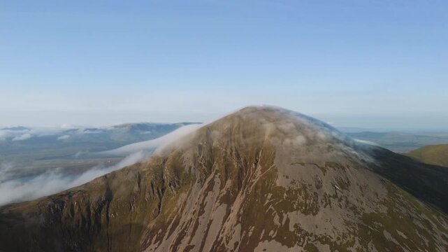 Amazing 4K aerial video of flying above and around Most Famous mountain in Ireland - Croagh Patrick in windy weather, with moving fog and clouds with breathtaking views around, Westport, Ireland