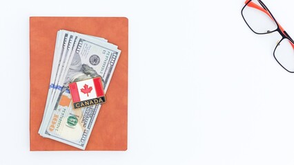 Canadian Investment Currency Stack with Flag Pin and Eyeglasses on White Background.