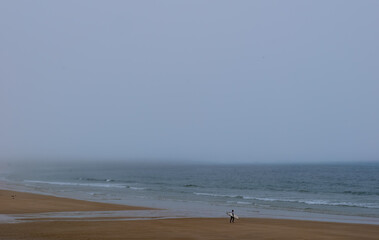 Man walking on the summer beach with waves and ocean water under the sky