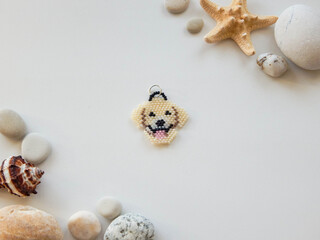 Cute keychain in the shape of a dog on a white background with seashells