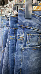 Close-up of blue denim jeans hanging on metal hangers in a clothing store