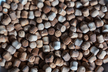 A close-up, high-angle shot of a pile of small, cylindrical light-brown, dried food - a traditional snack smoked kurut (kurt) - dried sour milk cheese (dried curd cheese).
