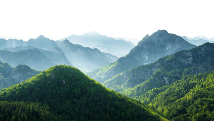 Obraz premium Majestic mountain range covered in verdant forests, with sunlight piercing through the misty peaks