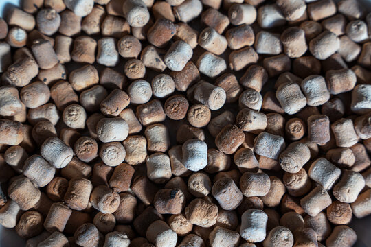 A close-up, high-angle shot of a pile of small, cylindrical light-brown, dried food - a traditional snack smoked kurut (kurt) - dried sour milk cheese (dried curd cheese).