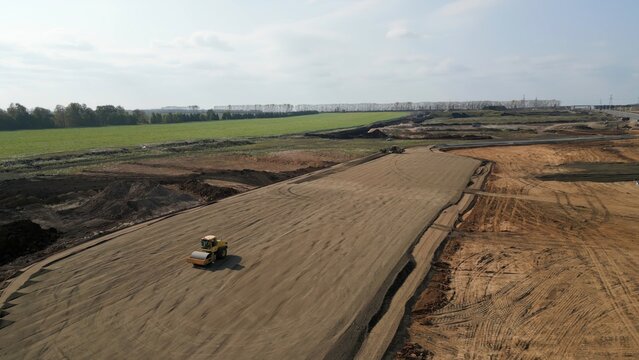 Road roller flattening ground at construction site. Clip