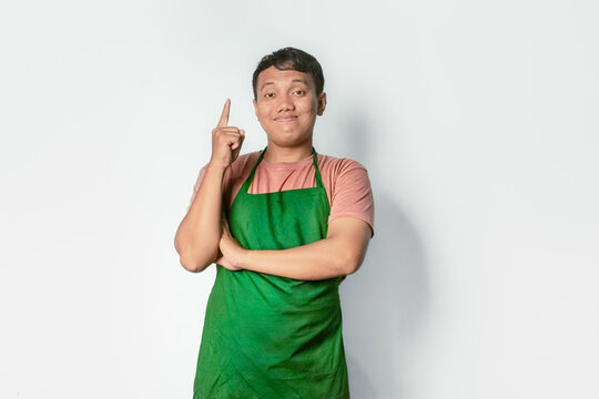 Asian man wearing green apron on white background with happy face and pointing his finger up, cooking and entrepreneurship concept
