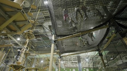 Kids playing on suspended net in indoor playground. Creative