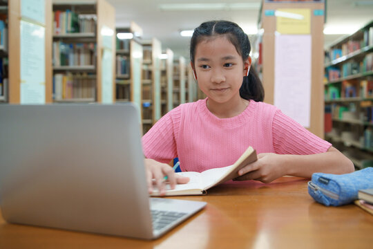 School student girl having video call on her computer in library at school.