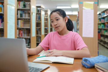 School student girl having video call on her computer in library at school.
