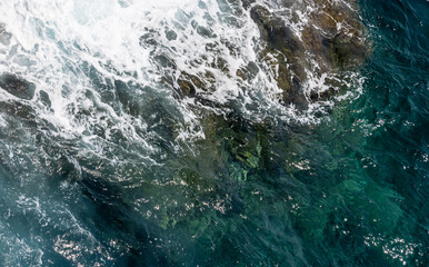 Aerial view of the turquoise sea meeting a rocky coast, natural photo background